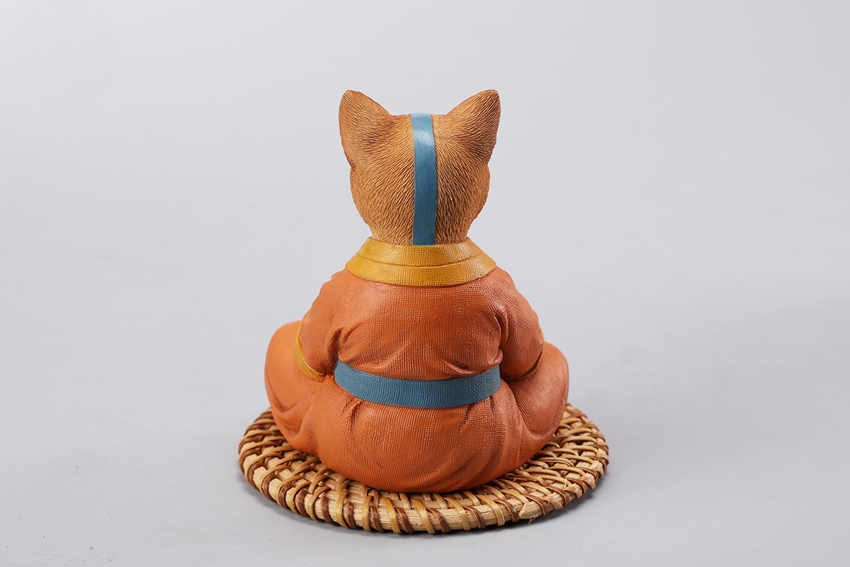 A handcrafted Airbender Cat Figurine in a meditative pose, dressed in an orange robe with a blue sash, sitting on a rattan-weaved cushion. This finely detailed resin sculpture captures the tranquility of mindfulness, perfect for cat lovers and meditation enthusiasts. An ideal collectible and decorative accent for any serene space.