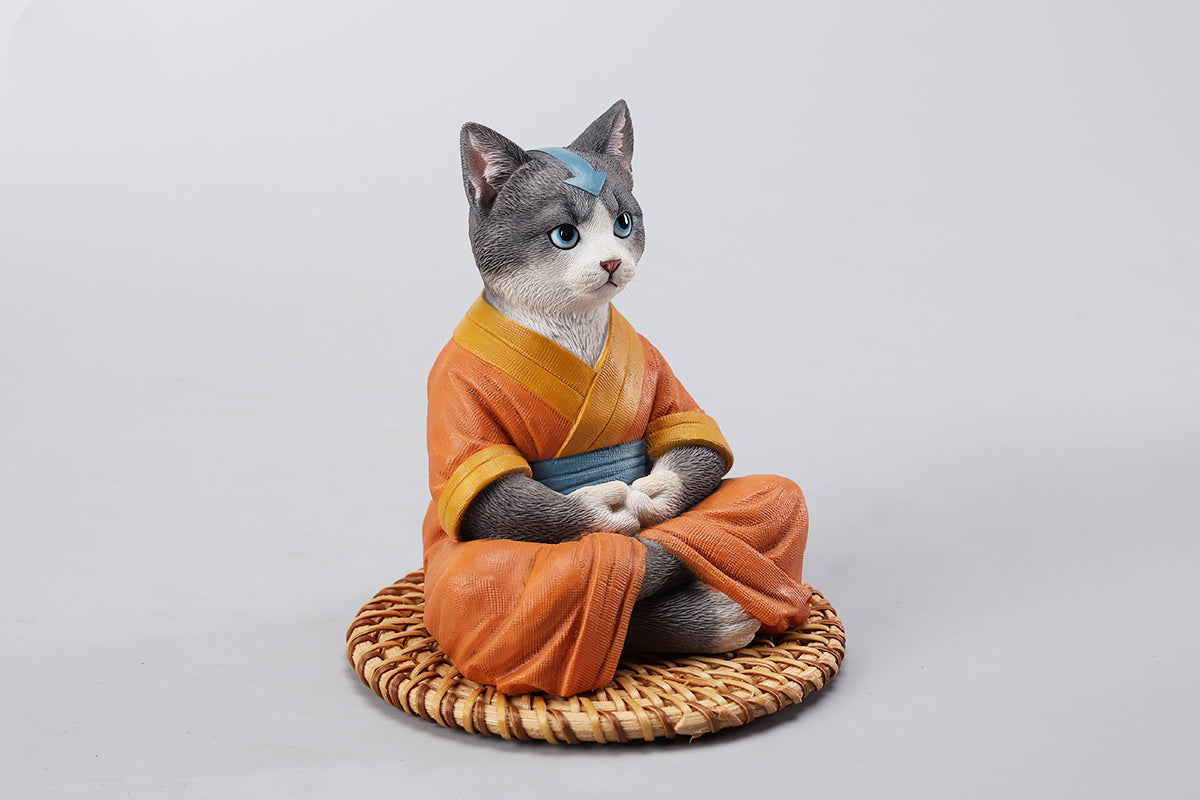 A handcrafted Airbender Cat Figurine in a meditative pose, dressed in an orange robe with a blue sash, sitting on a rattan-weaved cushion. This finely detailed resin sculpture captures the tranquility of mindfulness, perfect for cat lovers and meditation enthusiasts. An ideal collectible and decorative accent for any serene space.