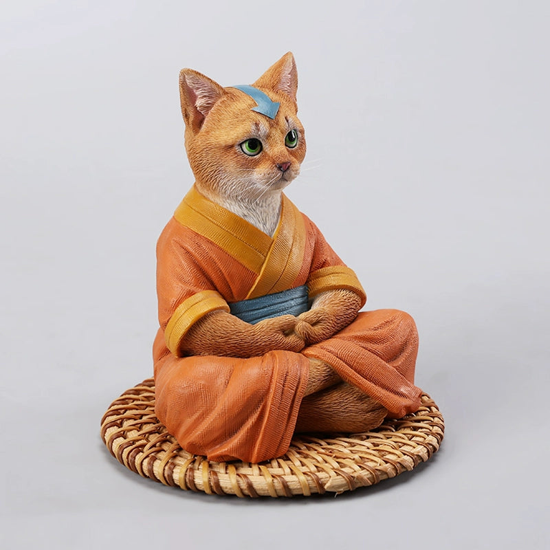 A handcrafted Airbender Cat Figurine in a meditative pose, dressed in an orange robe with a blue sash, sitting on a rattan-weaved cushion. This finely detailed resin sculpture captures the tranquility of mindfulness, perfect for cat lovers and meditation enthusiasts. An ideal collectible and decorative accent for any serene space.