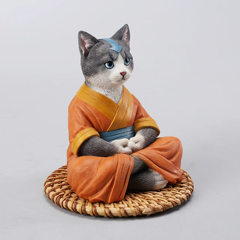 A handcrafted Airbender Cat Figurine in a meditative pose, dressed in an orange robe with a blue sash, sitting on a rattan-weaved cushion. This finely detailed resin sculpture captures the tranquility of mindfulness, perfect for cat lovers and meditation enthusiasts. An ideal collectible and decorative accent for any serene space.