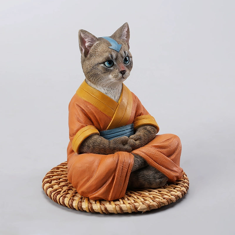A handcrafted Airbender Cat Figurine in a meditative pose, dressed in an orange robe with a blue sash, sitting on a rattan-weaved cushion. This finely detailed resin sculpture captures the tranquility of mindfulness, perfect for cat lovers and meditation enthusiasts. An ideal collectible and decorative accent for any serene space.