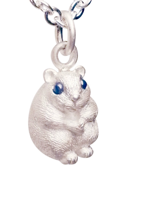 A handcrafted Fat Hamster Pendant made of 925 silver, featuring meticulously set gemstone eyes. The pendant showcases the adorable plumpness of a hamster, making it an ideal piece for pet memorial jewelry. Each pendant is unique, with slight variations in color and size, adding to its charm and individuality. Perfect for commemorating a beloved pet or as a gift for hamster lovers.