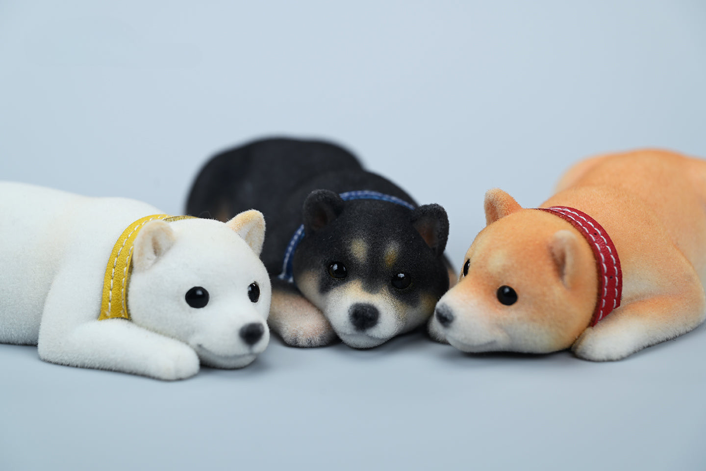 A set of three flocking Shiba Inu dog models in different colors - black, white, and tan. Each model features a realistic and adorable design with a collar in different colors: blue, yellow, and red. The dogs are shown in various poses, including waving, standing, and sitting.