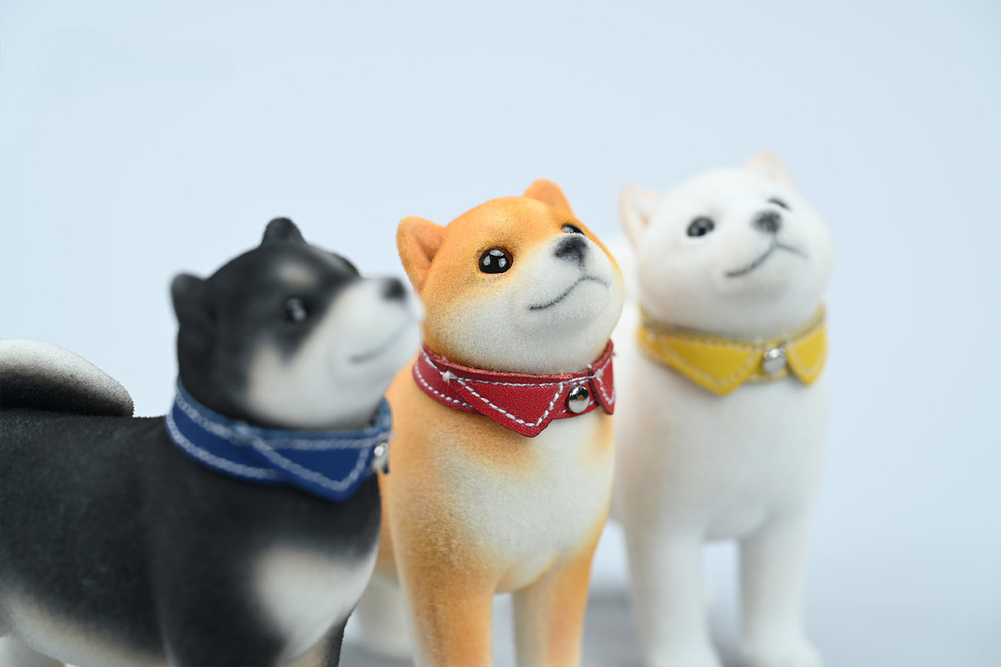 A set of three flocking Shiba Inu dog models in different colors - black, white, and tan. Each model features a realistic and adorable design with a collar in different colors: blue, yellow, and red. The dogs are shown in various poses, including waving, standing, and sitting.