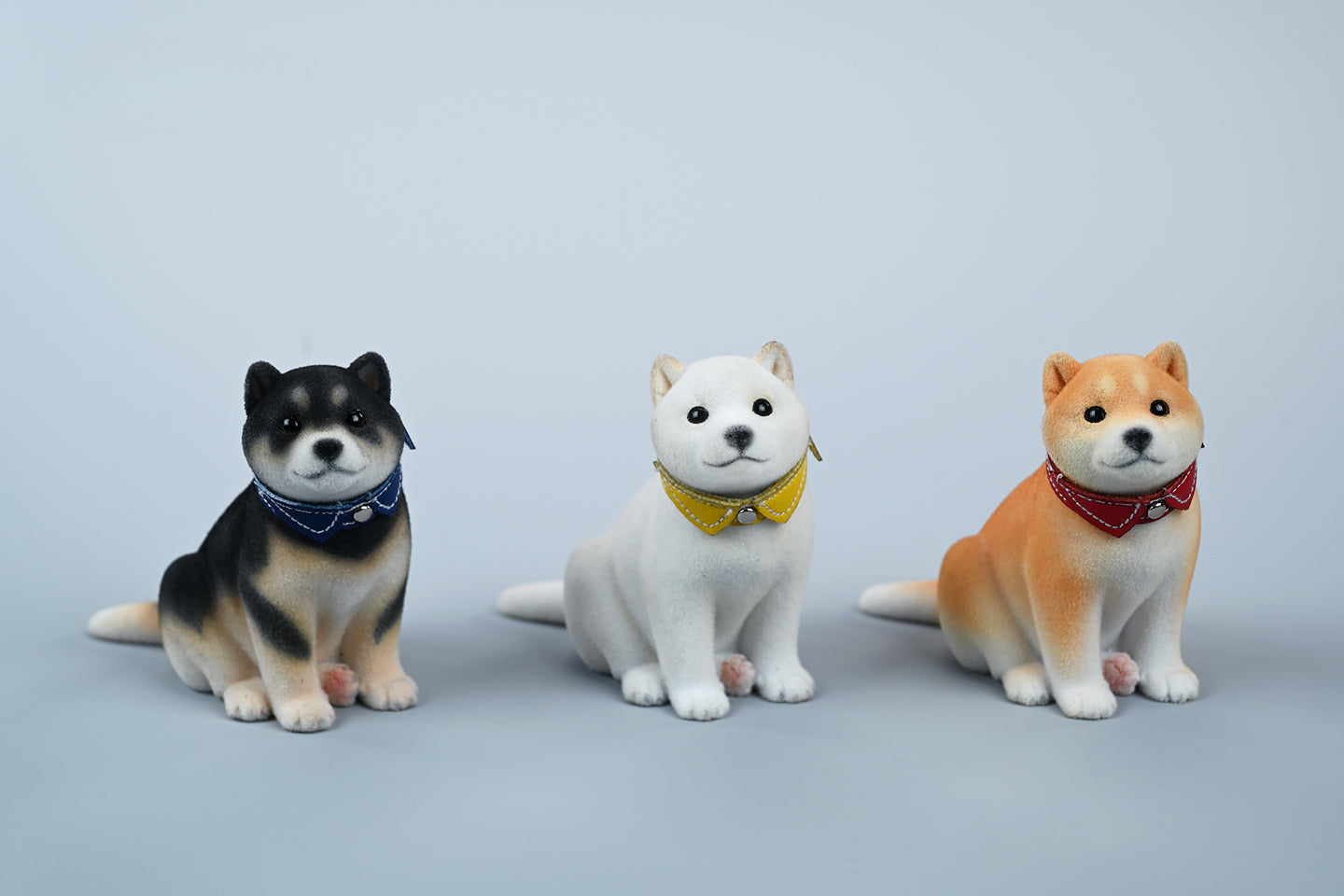 A set of three flocking Shiba Inu dog models in different colors - black, white, and tan. Each model features a realistic and adorable design with a collar in different colors: blue, yellow, and red. The dogs are shown in various poses, including waving, standing, and sitting.