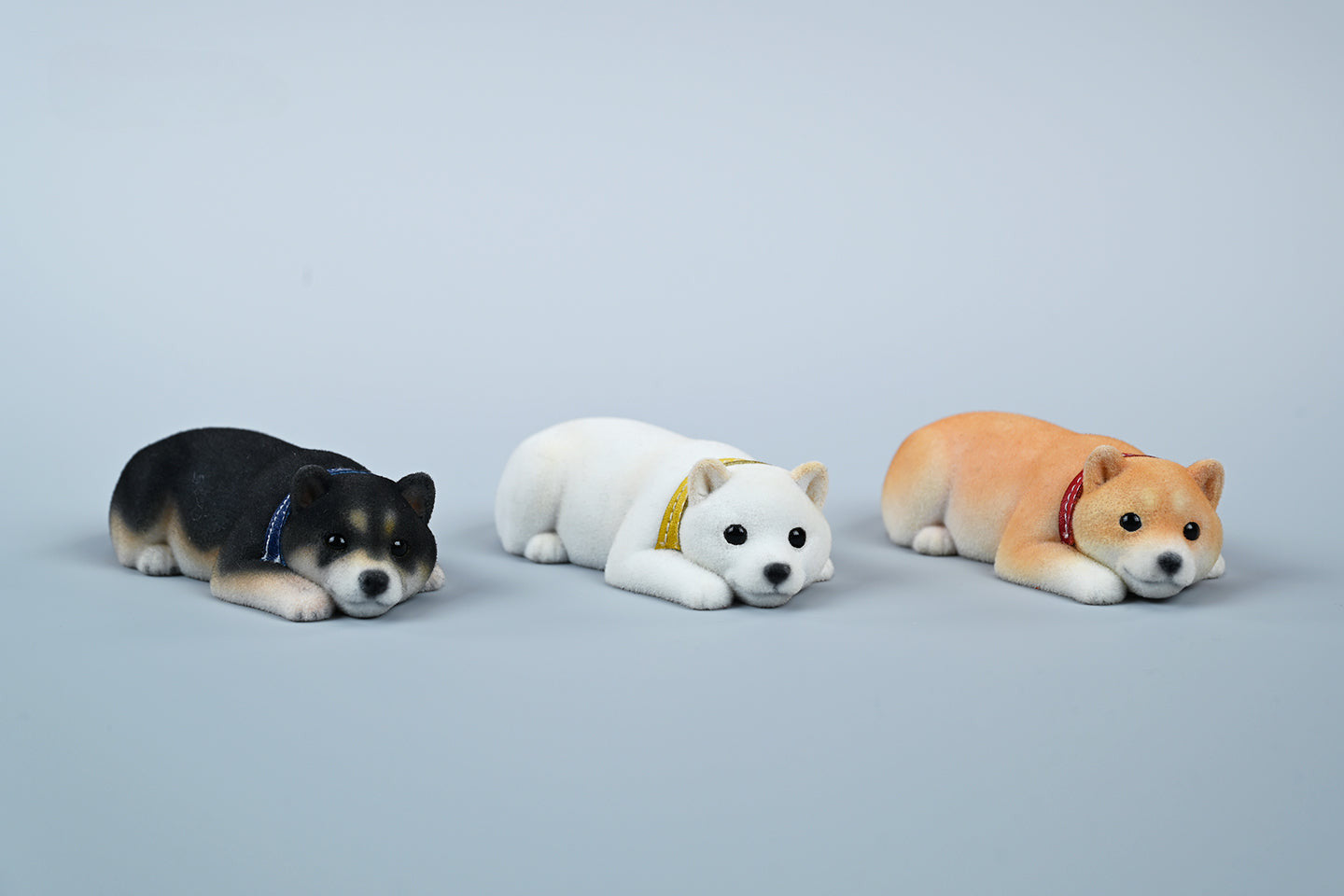 A set of three flocking Shiba Inu dog models in different colors - black, white, and tan. Each model features a realistic and adorable design with a collar in different colors: blue, yellow, and red. The dogs are shown in various poses, including waving, standing, and sitting.