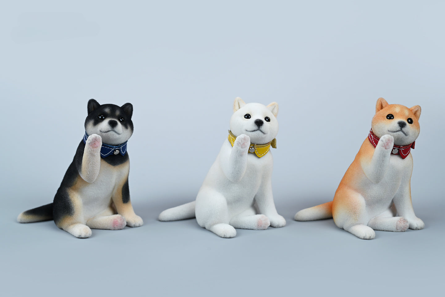 A set of three flocking Shiba Inu dog models in different colors - black, white, and tan. Each model features a realistic and adorable design with a collar in different colors: blue, yellow, and red. The dogs are shown in various poses, including waving, standing, and sitting.