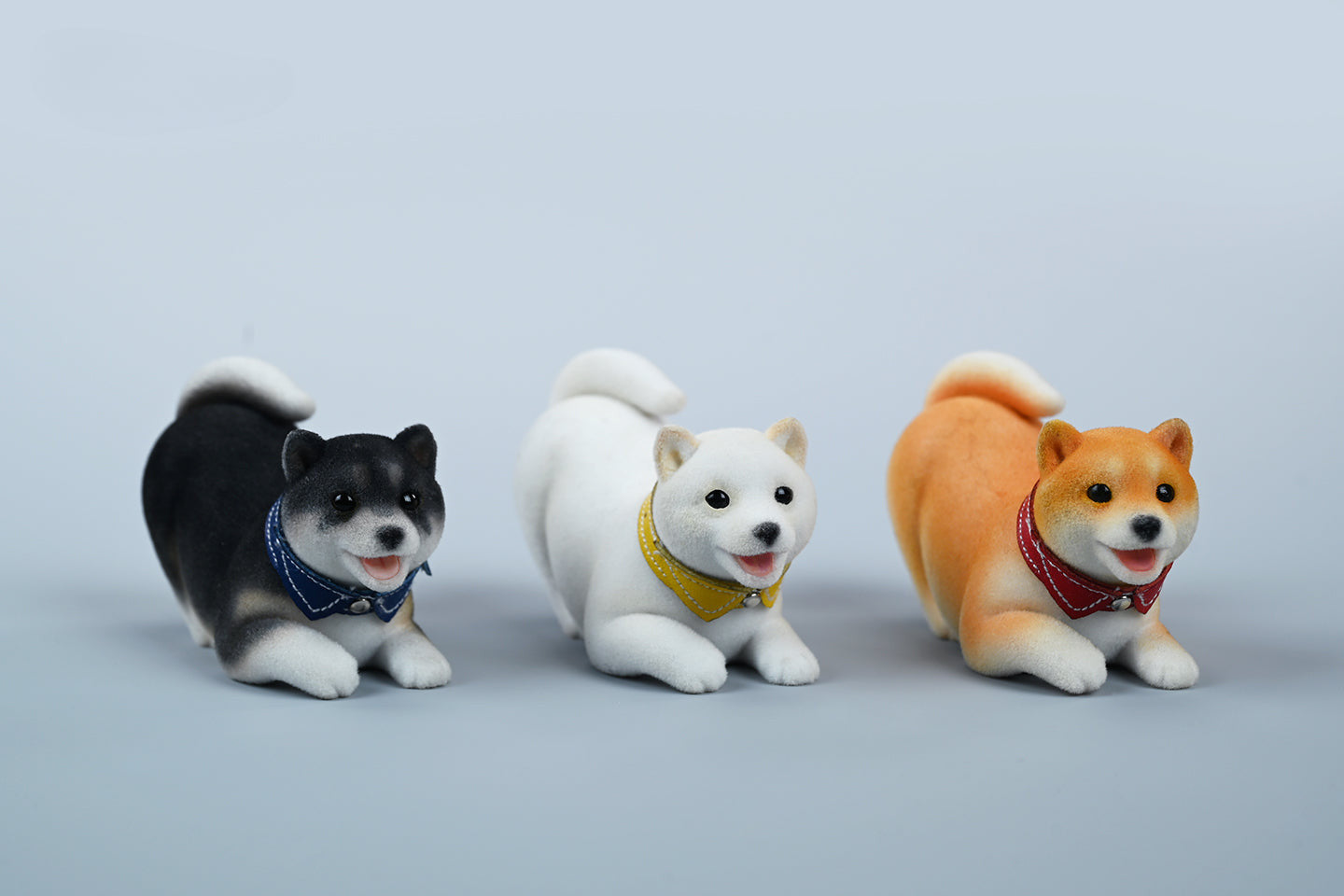 A set of three flocking Shiba Inu dog models in different colors - black, white, and tan. Each model features a realistic and adorable design with a collar in different colors: blue, yellow, and red. The dogs are shown in various poses, including waving, standing, and sitting.