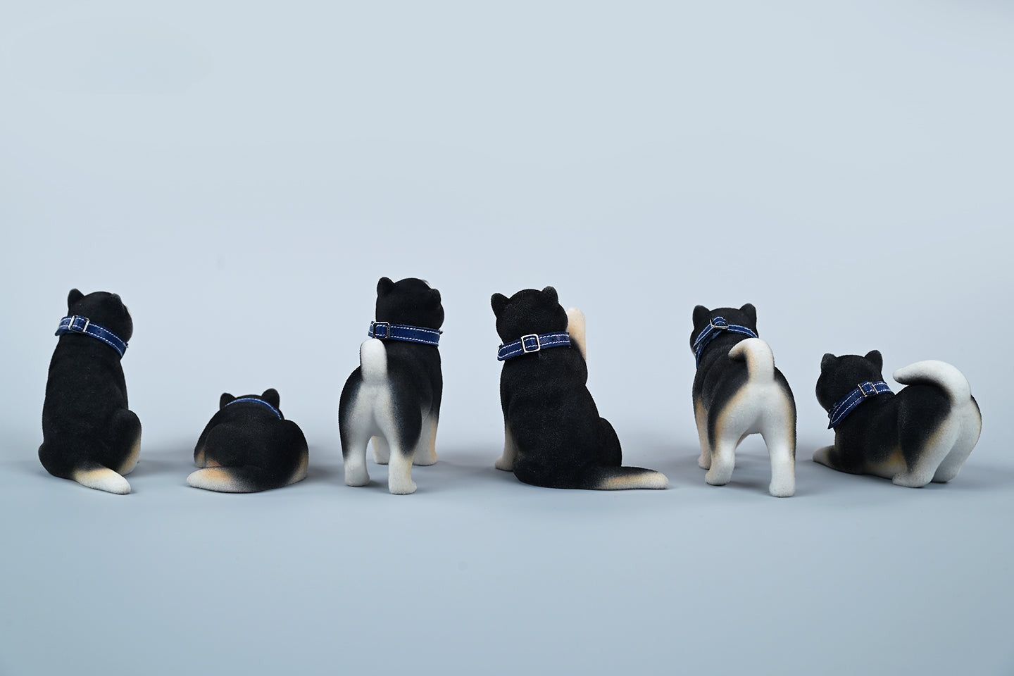 A set of three flocking Shiba Inu dog models in different colors - black, white, and tan. Each model features a realistic and adorable design with a collar in different colors: blue, yellow, and red. The dogs are shown in various poses, including waving, standing, and sitting.