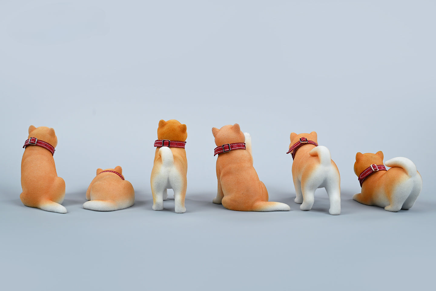 A set of three flocking Shiba Inu dog models in different colors - black, white, and tan. Each model features a realistic and adorable design with a collar in different colors: blue, yellow, and red. The dogs are shown in various poses, including waving, standing, and sitting.