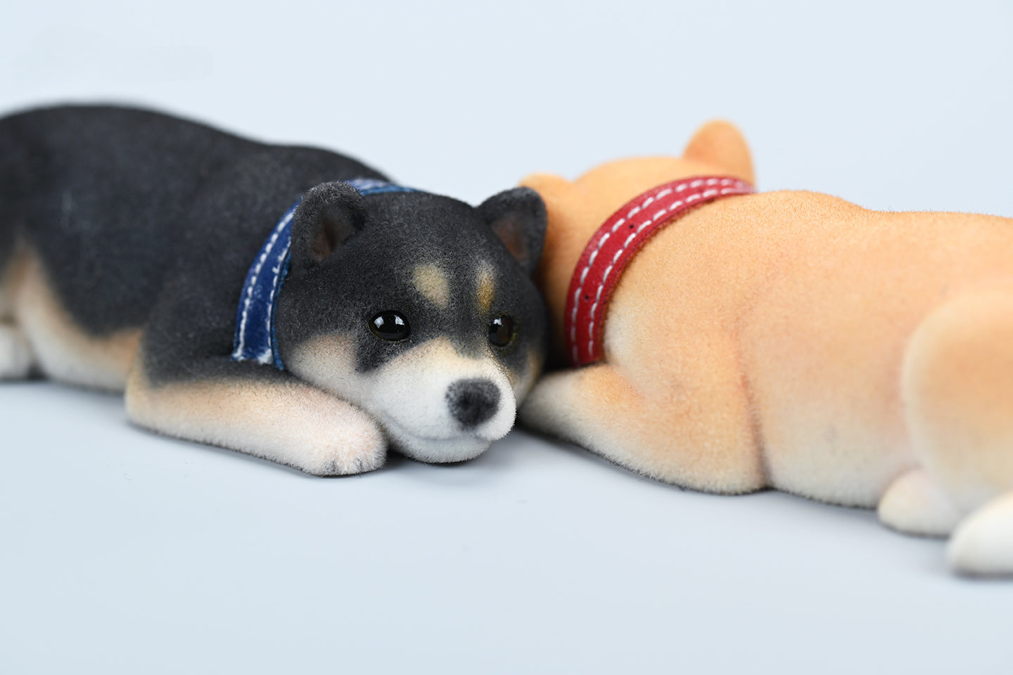 A set of three flocking Shiba Inu dog models in different colors - black, white, and tan. Each model features a realistic and adorable design with a collar in different colors: blue, yellow, and red. The dogs are shown in various poses, including waving, standing, and sitting.