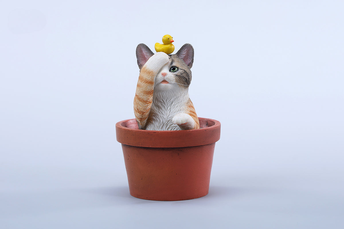 This charming Flower Pot Cat Model features a playful kitten peeking out of a terracotta pot with a small yellow rubber duck on its head. The series includes multiple variations, each with a different accessory atop the cat's head. This delightful ornament brings a touch of whimsy and cheer to any space, perfect for cat lovers and collectors alike. The detailed craftsmanship and vibrant colors make it a standout piece in any collection.