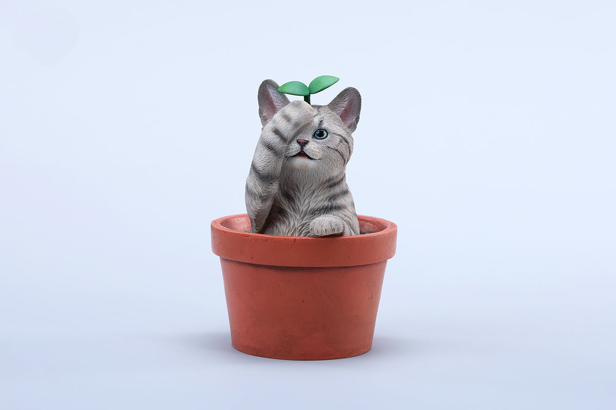 This charming Flower Pot Cat Model features a playful kitten peeking out of a terracotta pot with a small yellow rubber duck on its head. The series includes multiple variations, each with a different accessory atop the cat's head. This delightful ornament brings a touch of whimsy and cheer to any space, perfect for cat lovers and collectors alike. The detailed craftsmanship and vibrant colors make it a standout piece in any collection.