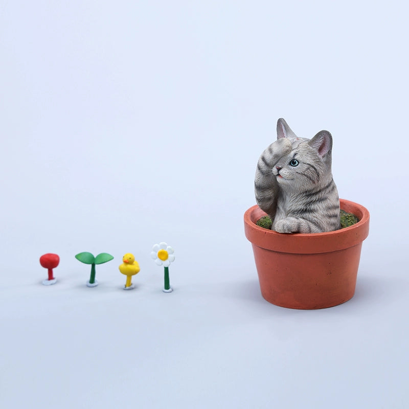 This charming Flower Pot Cat Model features a playful kitten peeking out of a terracotta pot with a small yellow rubber duck on its head. The series includes multiple variations, each with a different accessory atop the cat's head. This delightful ornament brings a touch of whimsy and cheer to any space, perfect for cat lovers and collectors alike. The detailed craftsmanship and vibrant colors make it a standout piece in any collection.