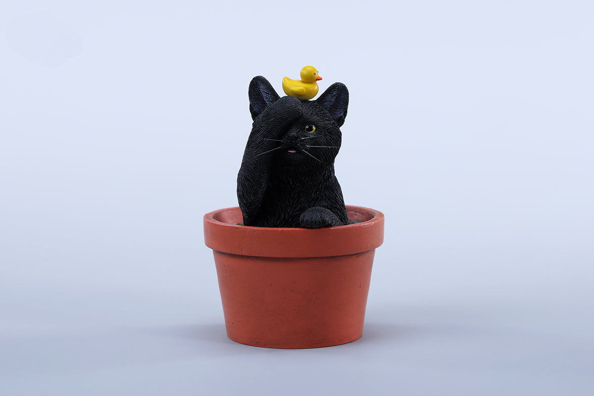 This charming Flower Pot Cat Model features a playful kitten peeking out of a terracotta pot with a small yellow rubber duck on its head. The series includes multiple variations, each with a different accessory atop the cat's head. This delightful ornament brings a touch of whimsy and cheer to any space, perfect for cat lovers and collectors alike. The detailed craftsmanship and vibrant colors make it a standout piece in any collection.