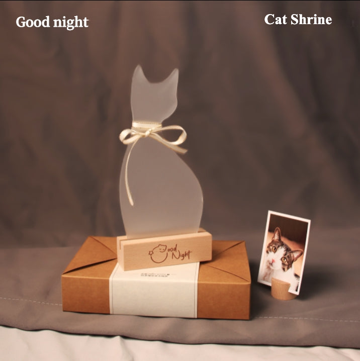 White ceramic cat-shaped pet cremation urn set with personalized memorial plaque, candle holder, fur keepsake box, photo stand, and woven mat, designed for home ashes storage and display.