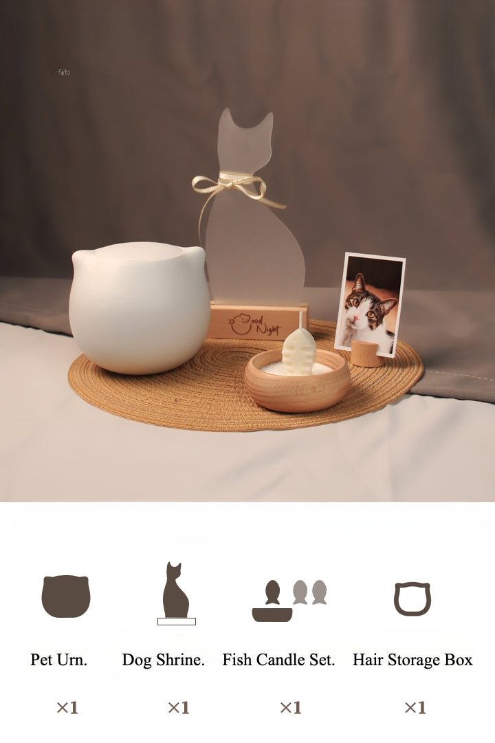 White ceramic cat-shaped pet cremation urn set with personalized memorial plaque, candle holder, fur keepsake box, photo stand, and woven mat, designed for home ashes storage and display.