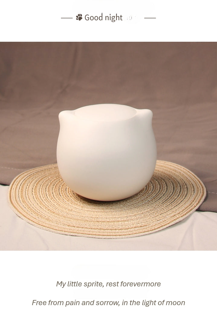 This white cat ceramic pet urn features a charming cat-shaped design with a detachable photo frame and included candle, measuring 15cm tall and 10cm wide, holding 200ml of ashes. Perfect for North American pet owners memorializing small pets like cats or kittens, it offers secure storage and a heartfelt display for shelves or mantels.