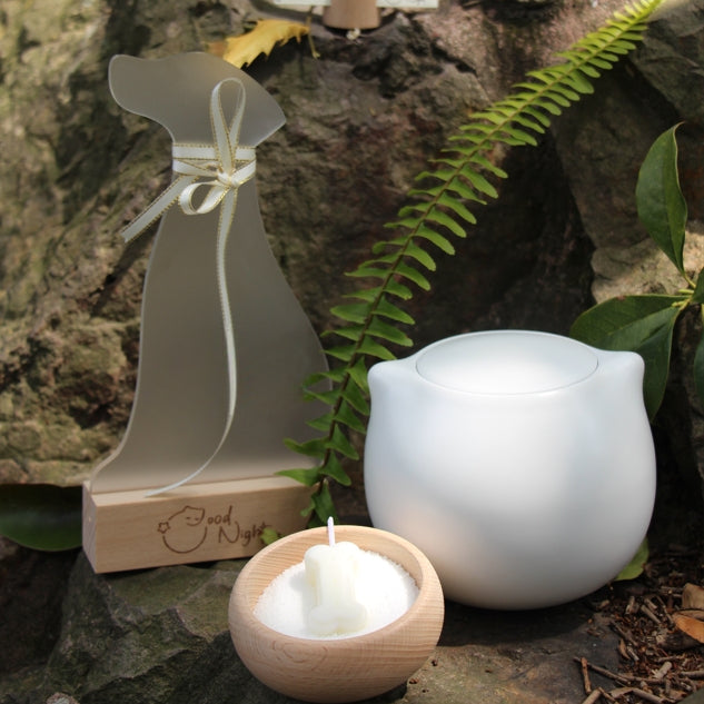 The Good Night Pet Memorial Set (Dog) includes a white ceramic pet urn with a silicone-sealed lid, dog shrine, bone candle set, and hair storage box, measuring 15cm tall and 10cm wide, holding 200ml for pets up to 25 pounds. Ideal for North American dog owners, it offers a warm, handcrafted memorial display for shelves or tables.