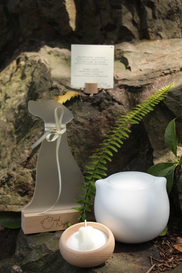 The Good Night Pet Memorial Set (Dog) includes a white ceramic pet urn with a silicone-sealed lid, dog shrine, bone candle set, and hair storage box, measuring 15cm tall and 10cm wide, holding 200ml for pets up to 25 pounds. Ideal for North American dog owners, it offers a warm, handcrafted memorial display for shelves or tables.