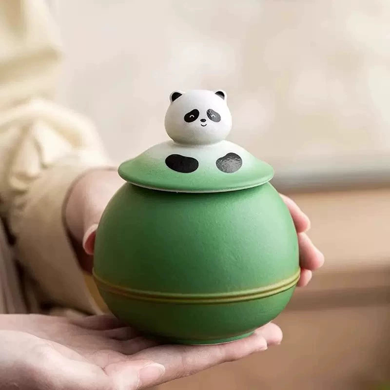 This green panda pet urn showcases a cute round ceramic design with a playful panda figurine on top, measuring 12.5cm wide, 11cm tall, and 9.1cm in diameter, holding 290ml of ashes. Ideal for North American pet owners honoring small pets like cats or dogs, it offers secure storage and a warm memorial display, fitting perfectly on shelves or mantels.