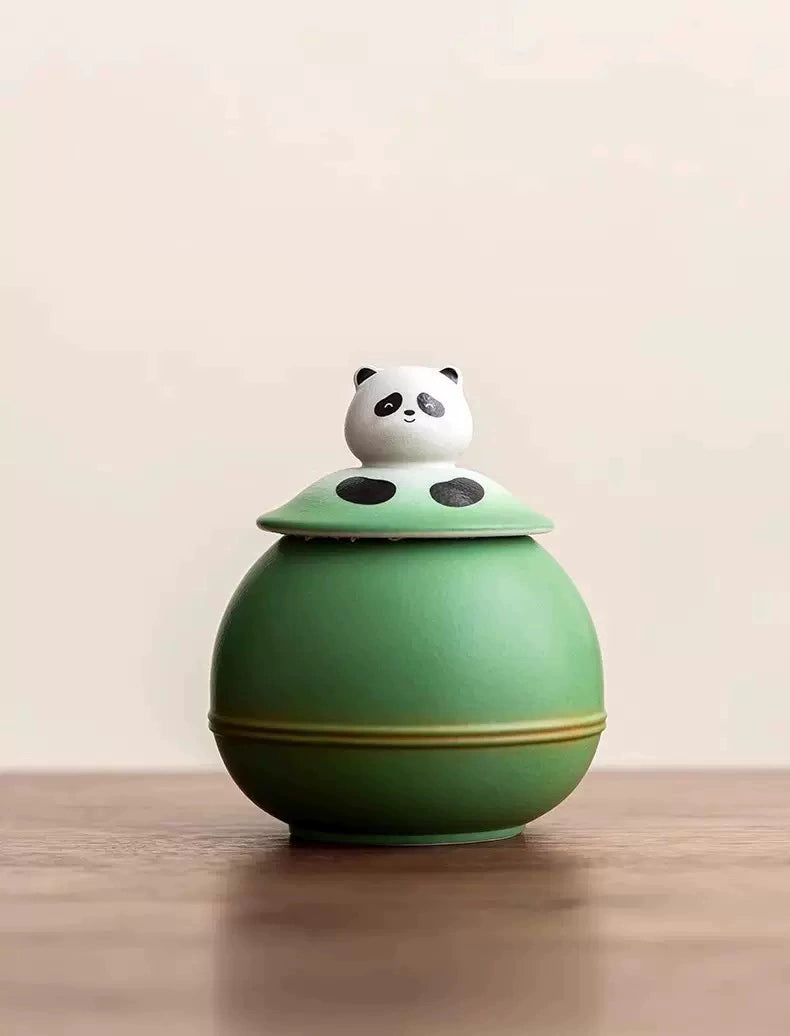 This green panda pet urn showcases a cute round ceramic design with a playful panda figurine on top, measuring 12.5cm wide, 11cm tall, and 9.1cm in diameter, holding 290ml of ashes. Ideal for North American pet owners honoring small pets like cats or dogs, it offers secure storage and a warm memorial display, fitting perfectly on shelves or mantels.