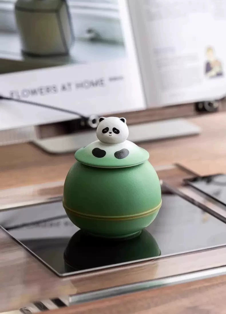 This green panda pet urn showcases a cute round ceramic design with a playful panda figurine on top, measuring 12.5cm wide, 11cm tall, and 9.1cm in diameter, holding 290ml of ashes. Ideal for North American pet owners honoring small pets like cats or dogs, it offers secure storage and a warm memorial display, fitting perfectly on shelves or mantels.