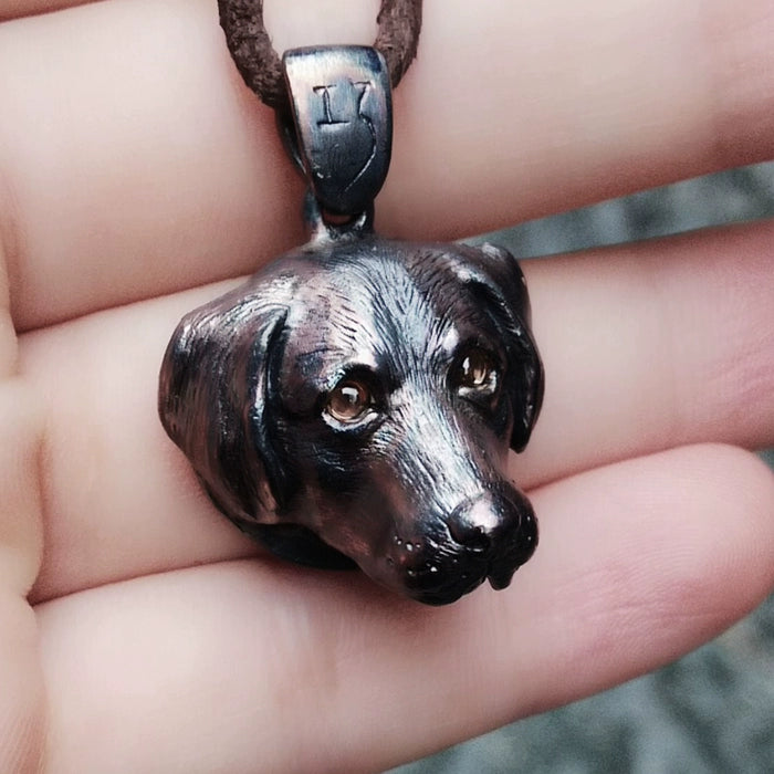 Close-up image of a handcrafted Labrador dog ring and pendant made from 925 sterling silver. The jewelry features intricate details and gemstone inlaid eyes, available in various colors such as black obsidian, red garnet, blue sapphire, green diopside, and brown smoky quartz. The pieces come in classic silver and antique black finishes, with optional custom engraving. Perfect as a pet memorial or dog lover gift.