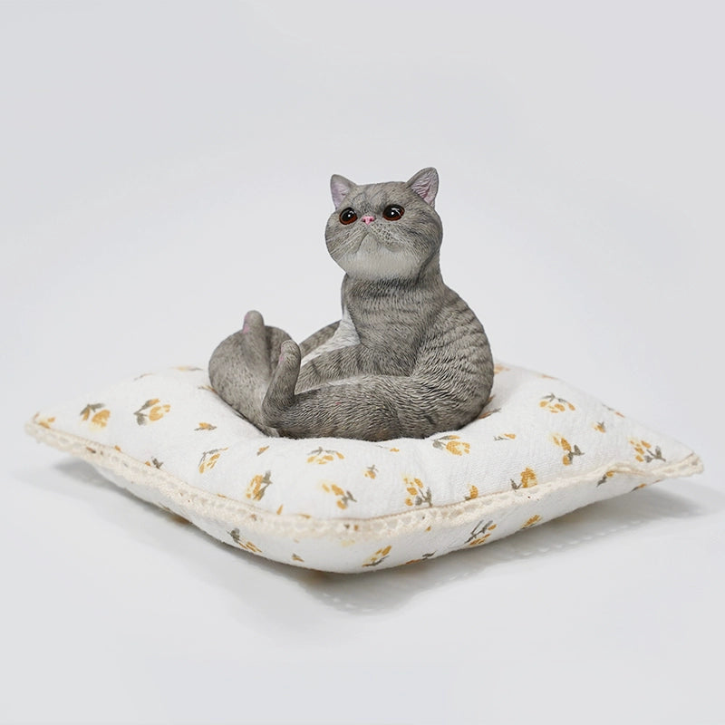 This image showcases a 1/6 Lazy Cat 8.0 Model, featuring an orange cat figurine sitting on a soft, floral-patterned cushion. The cat is in a relaxed pose, with its tail curled around its body and its front paws resting on its belly. The detailed design captures the cat's lifelike features, including its expressive eyes and realistic fur texture.