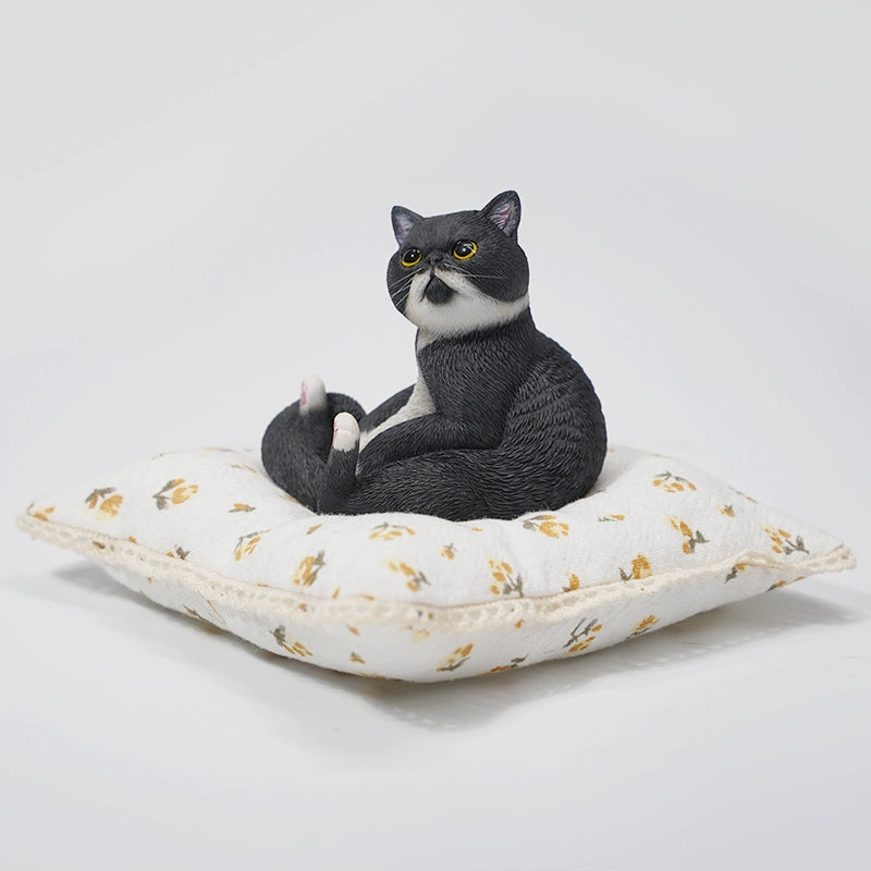 This image showcases a 1/6 Lazy Cat 8.0 Model, featuring an orange cat figurine sitting on a soft, floral-patterned cushion. The cat is in a relaxed pose, with its tail curled around its body and its front paws resting on its belly. The detailed design captures the cat's lifelike features, including its expressive eyes and realistic fur texture.