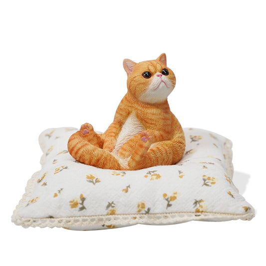 This image showcases a 1/6 Lazy Cat 8.0 Model, featuring an orange cat figurine sitting on a soft, floral-patterned cushion. The cat is in a relaxed pose, with its tail curled around its body and its front paws resting on its belly. The detailed design captures the cat's lifelike features, including its expressive eyes and realistic fur texture.