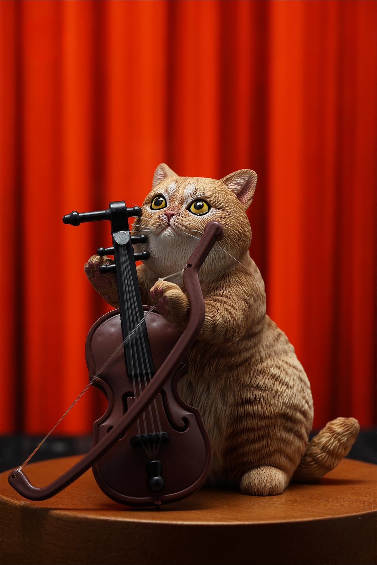 A lifelike string-playing cat figurine crafted from resin, featuring a realistic cat with expressive eyes playing a violin. The sculpture showcases intricate fur details and a beautifully designed musical instrument, making it an excellent collectible or home decor piece for cat lovers and music enthusiasts.