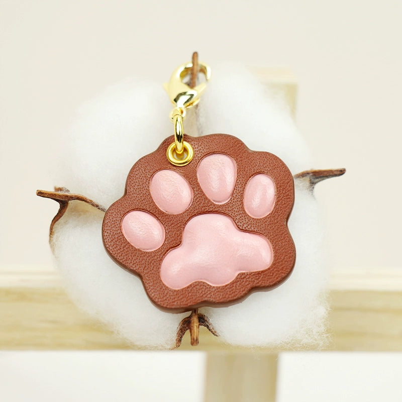 A collection of four handcrafted leather paw-shaped pendants in various colors, including black, green, tan, and white. Each pendant features a contrasting paw print, highlighting the high-quality craftsmanship and customizable options available. Ideal for pet owners who appreciate unique and personalized accessories.