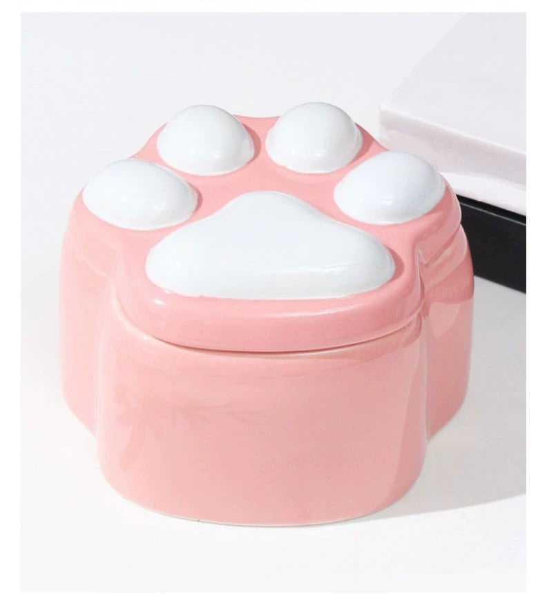 This pink and black paw ceramic pet urn features a stylish paw print lid, available in soft pink or sleek black, measuring approximately 12cm tall and 10cm wide. Crafted from durable ceramic, it offers secure storage for ashes of small to medium pets like cats or dogs, making it a heartfelt memorial display for North American pet owners on shelves or tables.