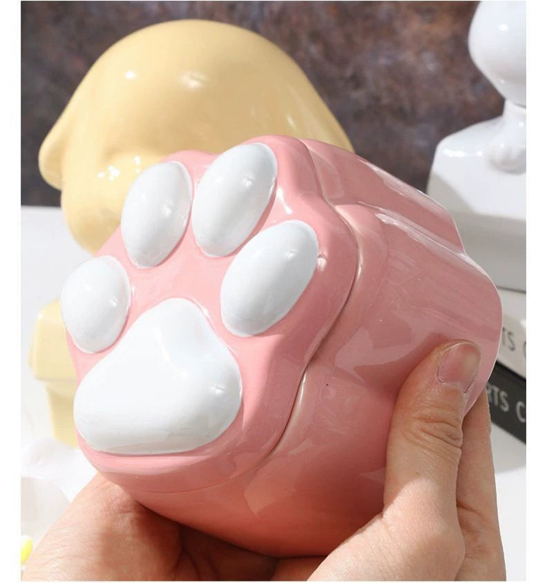 This pink and black paw ceramic pet urn features a stylish paw print lid, available in soft pink or sleek black, measuring approximately 12cm tall and 10cm wide. Crafted from durable ceramic, it offers secure storage for ashes of small to medium pets like cats or dogs, making it a heartfelt memorial display for North American pet owners on shelves or tables.