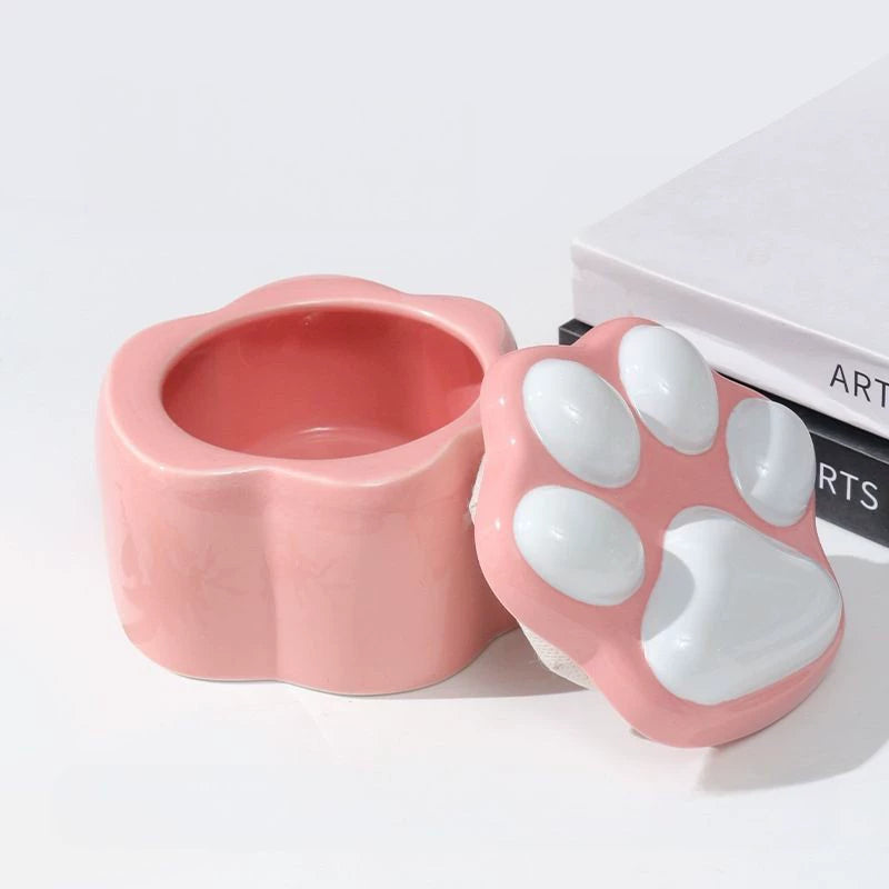 This pink and black paw ceramic pet urn features a stylish paw print lid, available in soft pink or sleek black, measuring approximately 12cm tall and 10cm wide. Crafted from durable ceramic, it offers secure storage for ashes of small to medium pets like cats or dogs, making it a heartfelt memorial display for North American pet owners on shelves or tables.
