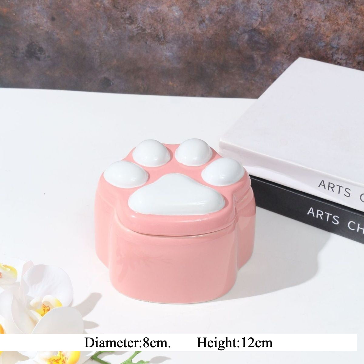 This pink and black paw ceramic pet urn features a stylish paw print lid, available in soft pink or sleek black, measuring approximately 12cm tall and 10cm wide. Crafted from durable ceramic, it offers secure storage for ashes of small to medium pets like cats or dogs, making it a heartfelt memorial display for North American pet owners on shelves or tables.