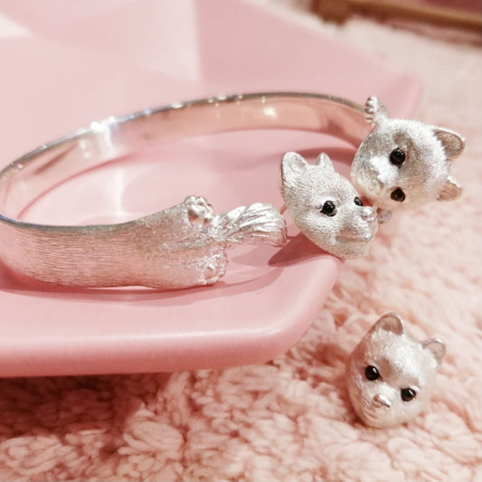 Close-up of Pomeranian-themed earrings and bracelet set, handcrafted from 925 sterling silver with intricate details and gemstone inlay eyes, showcasing the charming features of the Pomeranian breed.