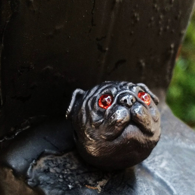 Close-up image of a handcrafted Pug Dog Head Charm made from 925 silver, featuring garnet gemstone eyes. The charm showcases intricate detailing with an antique black finish, perfect for dog lovers and jewelry collectors.