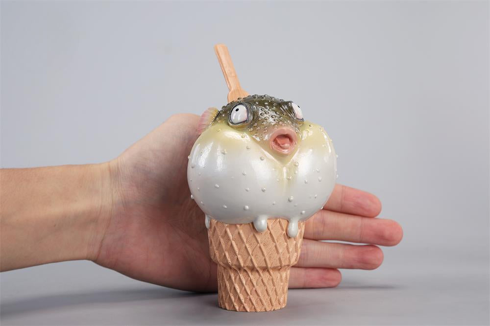 A highly detailed pufferfish ice cream figurine featuring a realistic fish with bulging eyes and textured scales, sitting on an intricately sculpted ice cream cone base. Made of premium resin, this collectible novelty item is perfect for unique decor lovers and marine life enthusiasts.