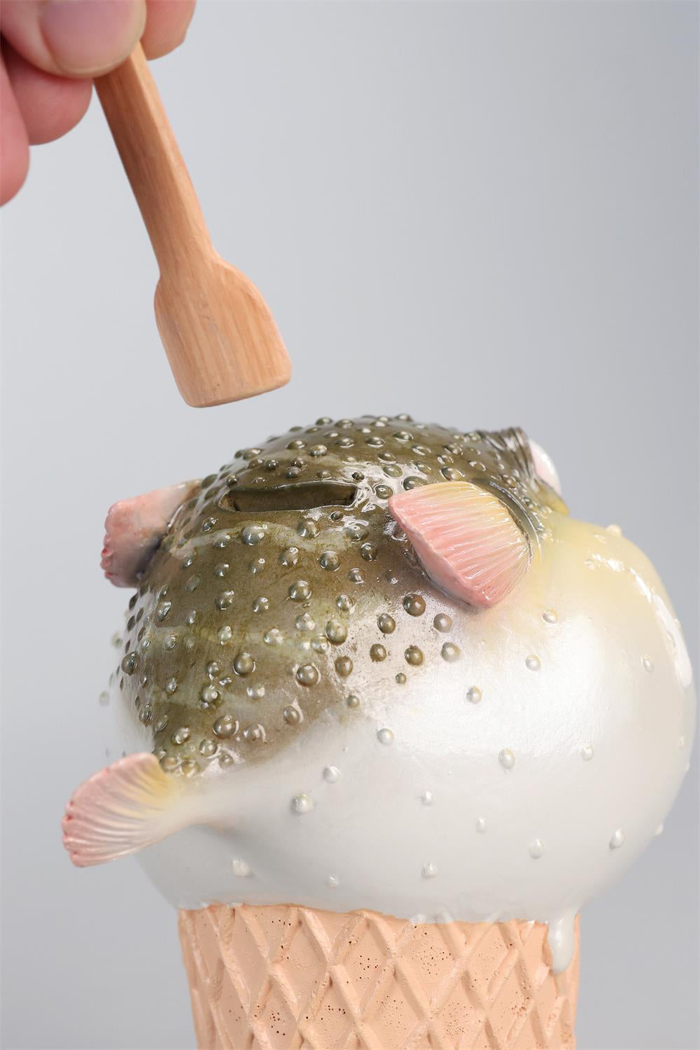 A highly detailed pufferfish ice cream figurine featuring a realistic fish with bulging eyes and textured scales, sitting on an intricately sculpted ice cream cone base. Made of premium resin, this collectible novelty item is perfect for unique decor lovers and marine life enthusiasts.