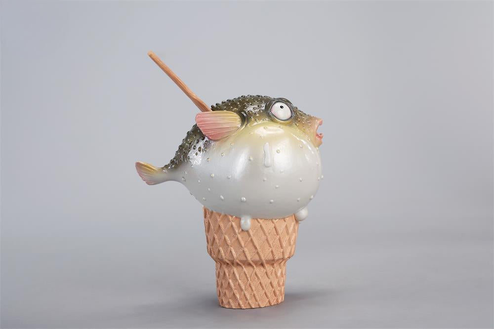 A highly detailed pufferfish ice cream figurine featuring a realistic fish with bulging eyes and textured scales, sitting on an intricately sculpted ice cream cone base. Made of premium resin, this collectible novelty item is perfect for unique decor lovers and marine life enthusiasts.