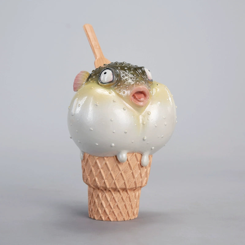 A highly detailed pufferfish ice cream figurine featuring a realistic fish with bulging eyes and textured scales, sitting on an intricately sculpted ice cream cone base. Made of premium resin, this collectible novelty item is perfect for unique decor lovers and marine life enthusiasts.