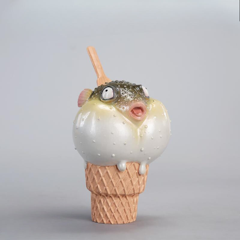 A highly detailed pufferfish ice cream figurine featuring a realistic fish with bulging eyes and textured scales, sitting on an intricately sculpted ice cream cone base. Made of premium resin, this collectible novelty item is perfect for unique decor lovers and marine life enthusiasts.