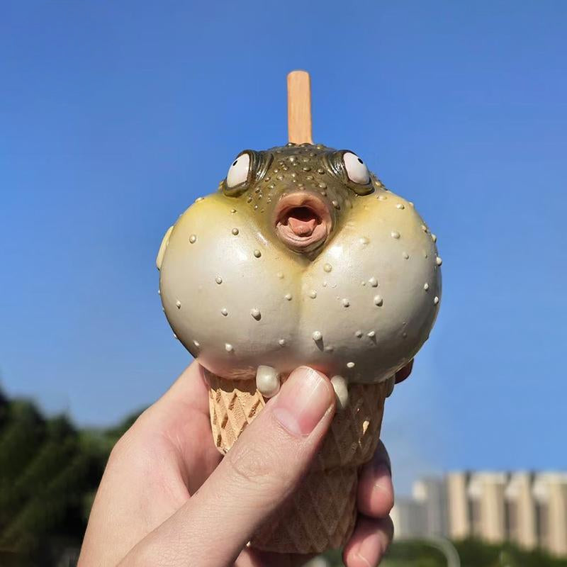 A highly detailed pufferfish ice cream figurine featuring a realistic fish with bulging eyes and textured scales, sitting on an intricately sculpted ice cream cone base. Made of premium resin, this collectible novelty item is perfect for unique decor lovers and marine life enthusiasts.