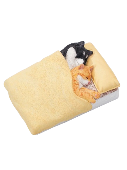 A charming figurine featuring a Shiba Inu dog snuggling with a cat under a yellow blanket. Both the dog and the cat are peacefully sleeping on a small bed, with detailed and realistic features that capture a heartwarming moment of companionship and comfort.