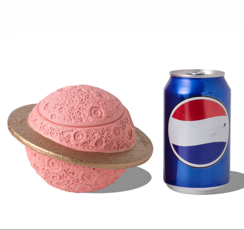 Discover the Pink Saturn-Shaped Pet Urn, a heartfelt memorial ashes holder crafted from durable Portland cement for North American pet owners. This whimsical planet-inspired design in soft pink, complete with a gold ring and textured craters, offers secure storage for up to 400ml of ashes from small pets. Measuring 16.5cm wide and 11cm tall, it weighs 1010g and fits perfectly on shelves or mantels, blending seamlessly into home decor. Ideal for cat or dog lovers seeking a unique tribute, it addresses grief 