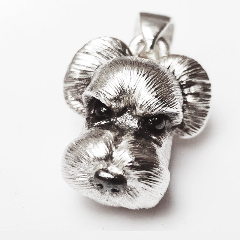 Close-up of a handcrafted Schnauzer pendant and ring set, made from 925 sterling silver with detailed fur texture and gemstone eyes, perfect for pet memorial jewelry.
