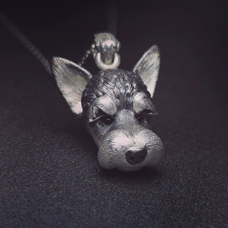 Close-up of a handcrafted Schnauzer pendant and ring set, made from 925 sterling silver with detailed fur texture and gemstone eyes, perfect for pet memorial jewelry.