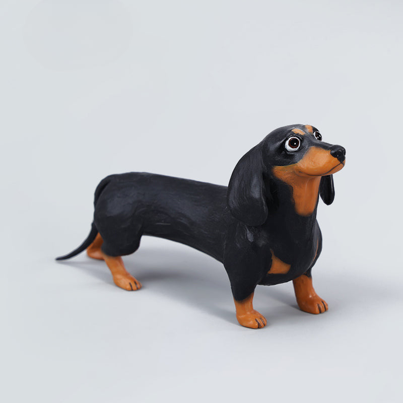 Two small clay Dachshund dog models, one black and one brown, captured in a realistic and lifelike manner. The models showcase detailed features, including expressive eyes and realistic fur textures. Perfect for collectors and dog enthusiasts.